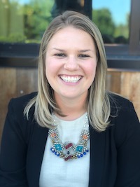 white woman with blond hair and a colorful necklace smiles at the camera